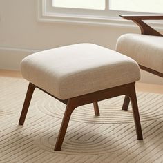 a chair and ottoman sitting on top of a carpeted floor next to a window