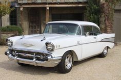 an old white car parked in front of a garage