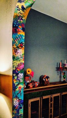 a living room with a fireplace and colorful wall paper on the back side of it