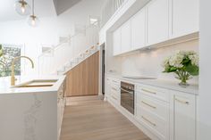 a kitchen with white cabinets and wooden flooring next to a staircase leading up to the second floor