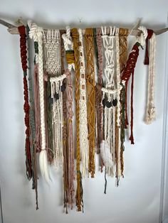 a wall hanging made out of macrame beads and tassels with feathers