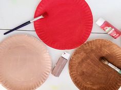 two paper plates with paint and brushes next to each other