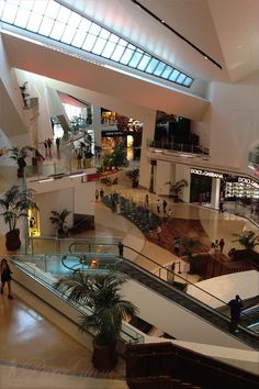 an overhead view of a mall with people walking down the escalator and shops in the background