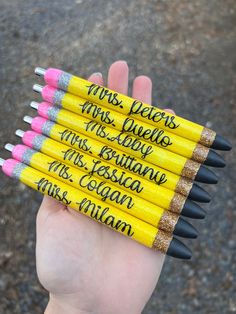 four yellow pencils with writing on them are held in a person's hand