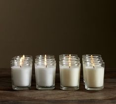 five candles lined up on a wooden table