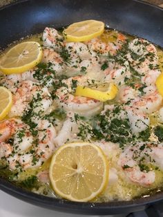 a skillet filled with shrimp and lemons on top of a stove burner