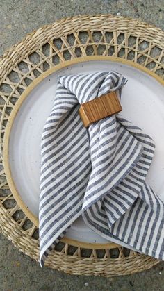 a plate with a napkin on it and a wooden bow tie around the edge, sitting on a wicker basket