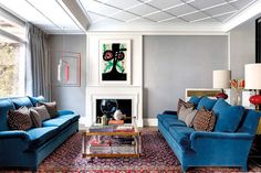 a living room filled with blue couches and a fire place under a painting on the wall