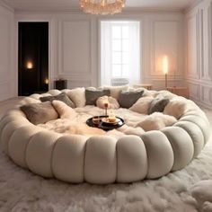 a large circular couch sitting in the middle of a living room next to a chandelier