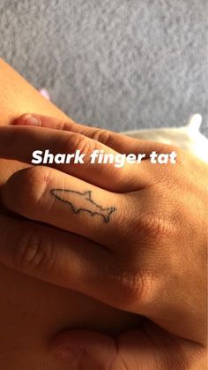 someone with a small tattoo on their left hand and the words shark finger tat