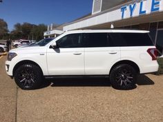 a white suv parked in front of a building with black rims and chrome wheels