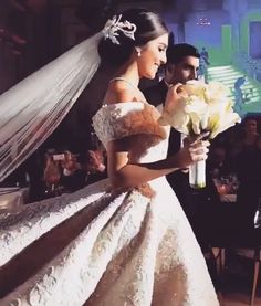 a woman in a wedding dress holding flowers next to a man wearing a tuxedo