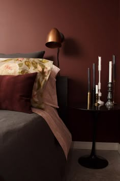 a bedroom with a bed, nightstand and two candles on the table in front of it