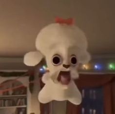 a white stuffed animal hanging from the ceiling with its tongue out and eyes wide open