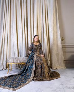 a woman in a blue and gold dress sitting on a chair next to a curtain