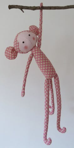 a pink monkey hanging from a tree branch