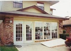 a car is parked in front of a house with large sliding glass doors and windows