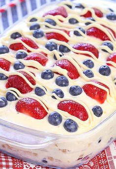 a dessert dish with strawberries, blueberries and cream in it on a table