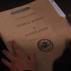 a person's hand on top of a brown box with the words federal bureau of investigating