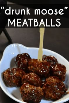 a white bowl filled with meatballs on top of a wooden skewer and the words drunk moose meatballs above it