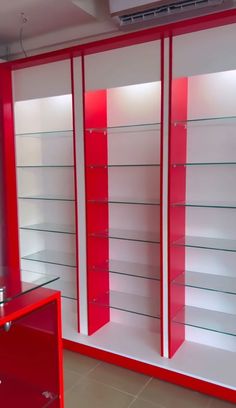 a red and white display case with glass shelves on the wall next to it's doors