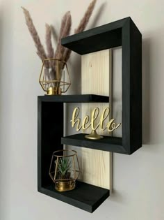 two black shelves with gold letters and some plants on one shelf that says, hello