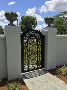 an iron gate in front of a white brick fence