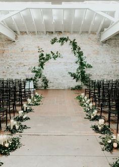 an outdoor ceremony with white candles and greenery on the aisle, surrounded by black chairs