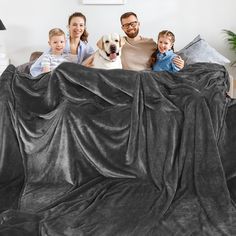 a family sitting on a couch with a dog and two children in front of them