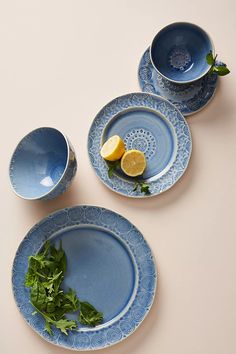 three blue plates with lemons and greens on them sitting next to each other in front of a white background