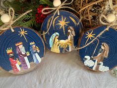 three wooden ornaments with nativity scenes painted on them