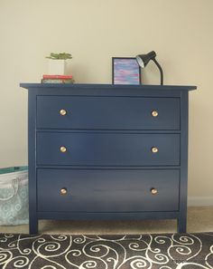 a blue dresser with gold knobs in a room next to a black and white rug