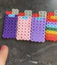 a hand is pointing at some colorful pegs on the floor with holes in them