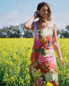 a woman standing in a field talking on a cell phone