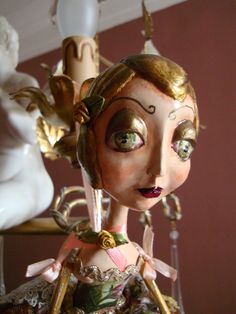 a close up of a figurine on a shelf near a lamp and statue