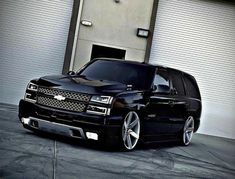 a black truck parked in front of a garage door with its hood up and wheels down