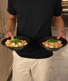 a man holding two black plates filled with food