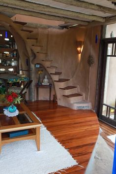 a living room filled with furniture next to a wooden table and stairs in the wall