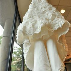 white wedding dress hanging from the ceiling in front of a window