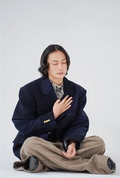 a man sitting on the ground with his hands clasped to his chest and eyes closed