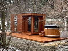 a hot tub sitting on top of a wooden deck next to some trees and snow