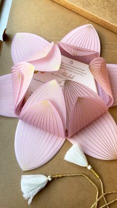 some pink paper with tassels on top of it