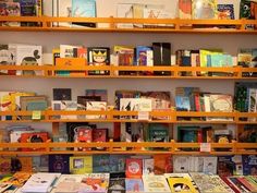 many books are lined up on shelves in a room with yellow walls and wooden shelving