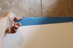 a person's hand reaching for something on the wall next to a tile floor