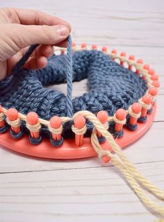 someone is knitting something on top of a circular object with yarn and beads around it