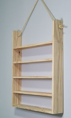 a wooden shelf hanging on a wall with rope attached to the bottom and two shelves below it