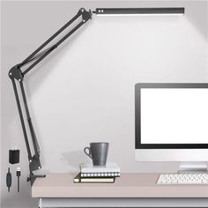 a computer desk with a monitor, keyboard and mouse next to a lamp on the wall