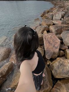 a woman sitting on rocks near the water