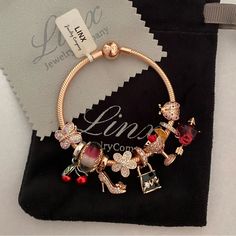 a bracelet with charms on it sitting on top of a black velvet bag next to a tag