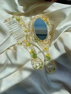 a comb and mirror sitting on top of a white satin covered table cloth next to the ocean